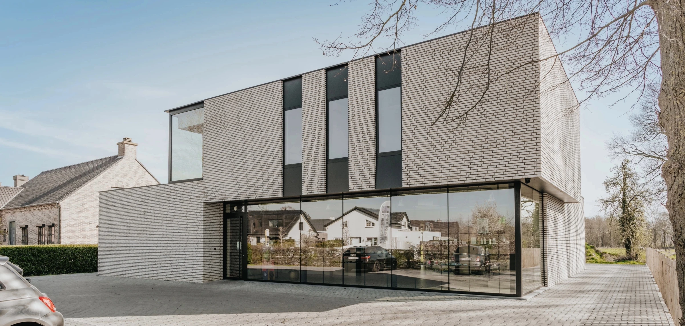 Een modern, strak vormgegeven kantoorpand met een opvallende gevel van lichtgrijze bakstenen en grote glaspartijen op de begane grond.