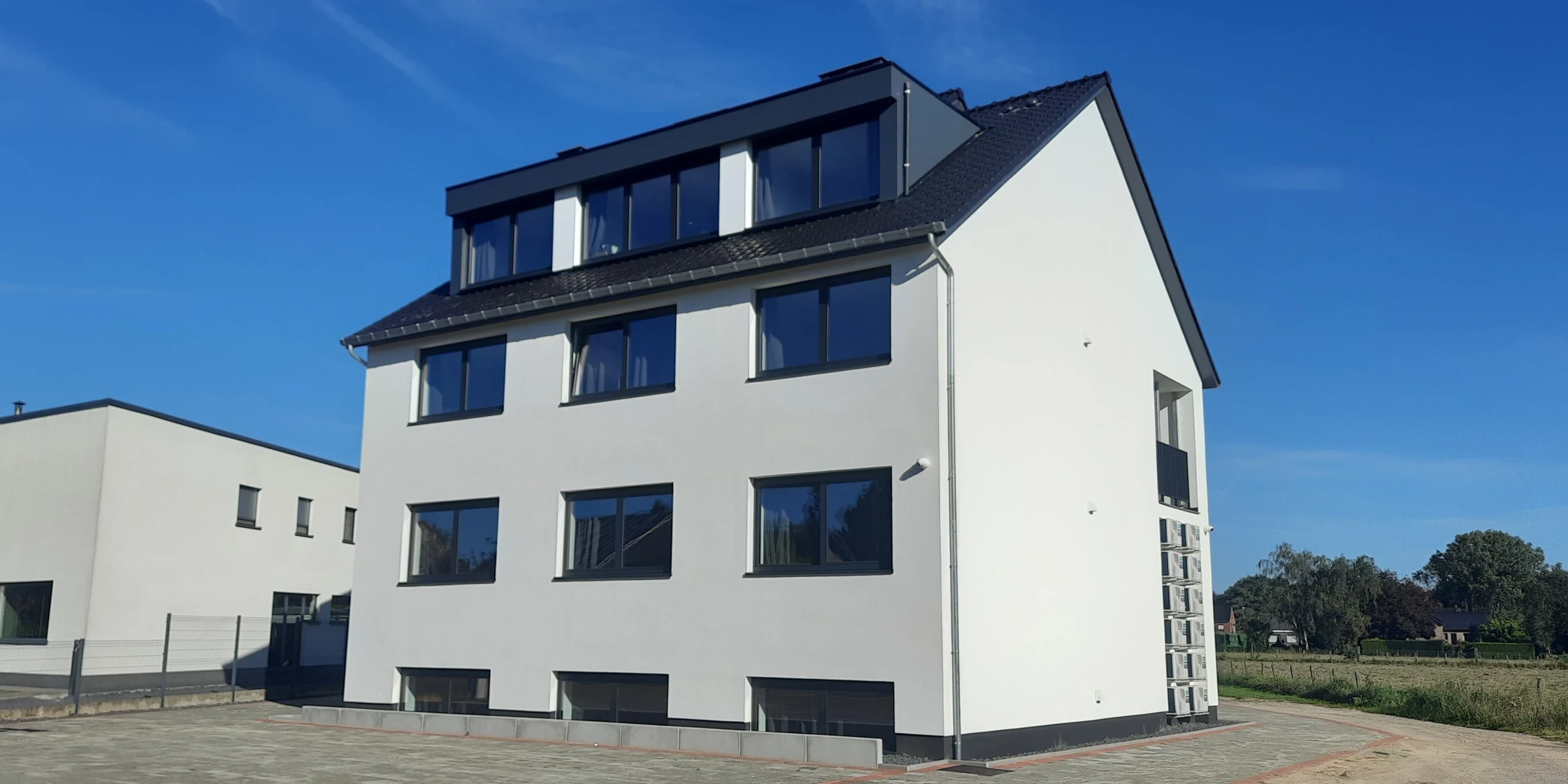 Realisatie: succesvolle verbouwing van een ruim studentenhuis met strakke witte gevelbepleistering en donkere kozijnen.